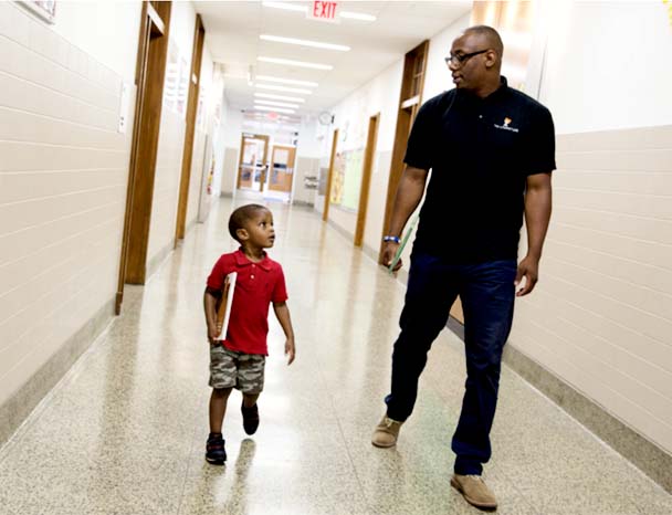 Child and adult walking down school hall